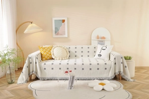 Detail of light beige throw cover with grey geometric dots and delicate fringe edge