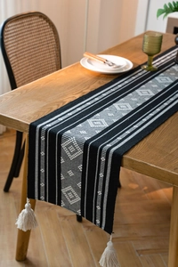 Detail of black and white geometric jacquard table runner with decorative cotton tassels