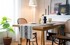 Dettaglio del runner da tavola bohémien con motivi geometrici bianchi e neri e nappe decorative