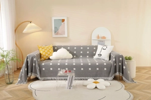 Detailed close-up of gray cotton sofa cover featuring white square grid and elegant tassels