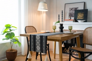 Close-up of monochrome geometric jacquard table runner with decorative white tassels