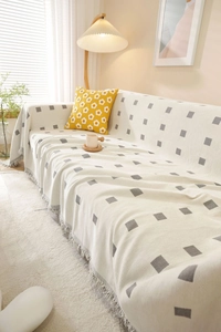 Detail of minimalist cream sofa cover with grey geometric pattern and fringed edges