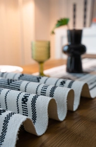 Dettaglio del runner da tavola jacquard bohémien con motivi geometrici neri e frange