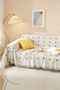 Detail showing cream thick textured sofa cover with gray geometric grid and fringe edge