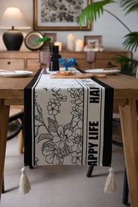 Close-up of jacquard floral table runner with tassels and Happy Life print