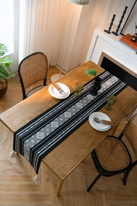 Detail of bohemian geometric jacquard table runner with tassel on wooden table