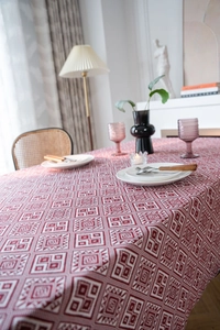Detail of red jacquard rectangle tablecloth with vintage geometric patterns in home setting