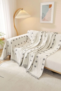 Close-up of thick woven sofa throw with grey geometric squares and tassel edges