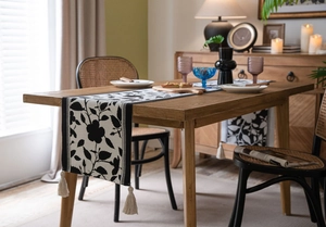 Detail of jacquard table runner with black and white floral pattern and cream tassels
