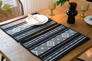 Close-up of bohemian table runner with geometric diamond patterns and tassel details