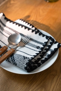 Dettaglio del runner da tavola con motivi geometrici, frange e posate eleganti