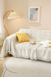 Detail of cream sofa throw with green geometric patterns and soft fringed edges
