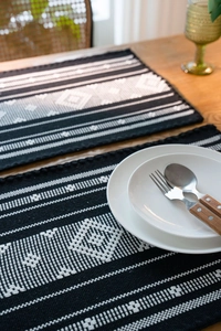 Close-up of bohemian woven table runner with black and white geometric jacquard pattern