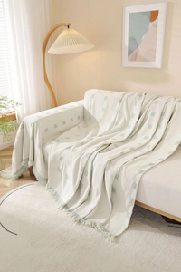 Close-up of cream cotton sofa cover with green square patterns and tassel fringe details