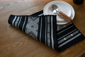 Detail of woven table runner with black and white geometric patterns on a wooden surface