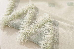 Close-up of thick geometric woven fabric with tassel edge and soft knitted texture