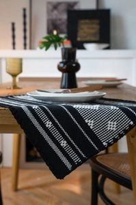 Close-up of woven table runner with black and white geometric patterns and fringe detail