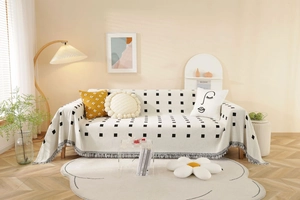 Detail of minimalist geometric sofa cover with black square patterns and fine tassels