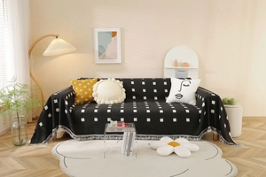 Close-up of thick black sofa cover with white geometric squares and fringe tassels