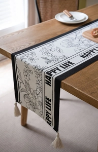 Detail of floral jacquard table runner with Happy Life text and cream tassels