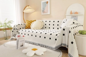 Detail of Nordic geometric knit sofa cover featuring tassels and small black square patterns