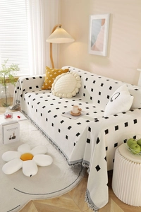 Close-up of thick geometric throw blanket with black square patterns and fringe details