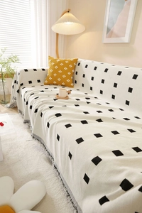 Close-up of geometric knit throw blanket with fringe edges and square dot patterns
