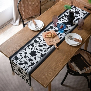 French minimalist jacquard table runner with black and white floral patterns and tassels