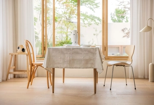 Detailed view of cream linen tablecloth with woven grid patterns on a wooden dining table