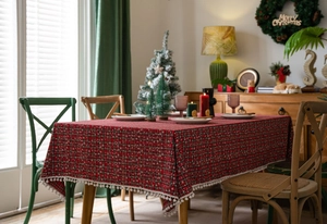 Detail van rood geruit kersttafelkleed met sneeuwvlokken en witte pompon-afwerking