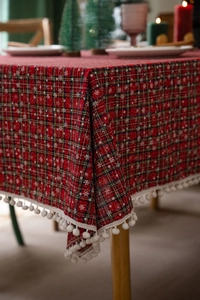 Detail van rood en groen geruit kersttafelkleed met witte pompon afwerking voor decoratie