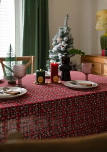 Detail van rood geruit kersttafelkleed met witte sneeuwvlokken en linnen textuur