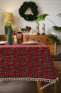 Detail van een rood geruit kersttafelkleed met witte sneeuwvlokken en pompon-afwerking