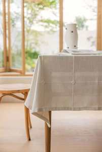 Detail of waffle weave linen tablecloth with decorative knots in a warm home setting