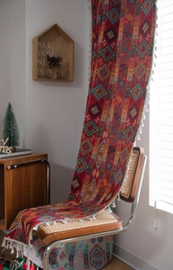 Detailed view of red bohemian woven curtain with geometric patterns and white tassels