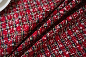 Detailopname van rood geruit tafelkleed met witte sneeuwvlokken en geweven textuur