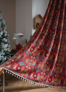 Close-up of red bohemian jacquard blanket with geometric patterns and white fringe details