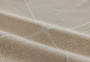 Macro shot of minimalist beige cotton linen tablecloth with delicate star embroidery