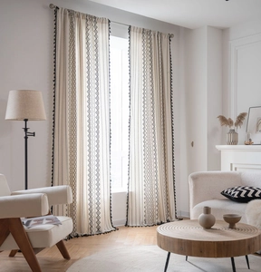 Close-up of bohemian linen curtain featuring black geometric prints and fringe tassels