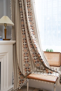 Detailed view of bohemian linen curtain with orange geometric patterns and tassel edges