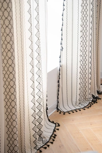 Close-up of cotton linen curtain featuring black bohemian geometric patterns and tassels