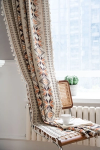 Close-up of geometric snowflake jacquard weave and white tassels on a rustic cotton curtain