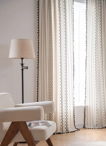 Detail of bohemian cotton linen curtain featuring black geometric prints and tassels