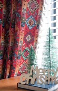 Detail of red Bohemian jacquard curtain featuring geometric patterns and white pompom fringe