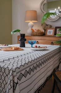 Détail d'une nappe bohème en coton et lin avec motifs géométriques noirs et franges