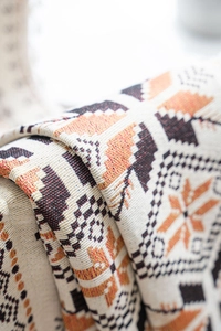 Detailed close-up of bohemian floral jacquard weave fabric with orange and beige patterns