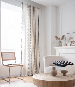 Detail of bohemian cotton linen curtain with black geometric patterns and fringe tassels