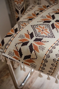 Detail of bohemian jacquard fabric with floral patterns and white decorative tassels