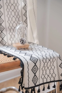 Detail of bohemian cotton linen table runner with black geometric print and tassels