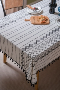 Détail de nappe bohème avec motif géométrique noir et blanc et bordure à pompons